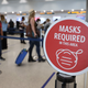 A sign reading, ‘masks required in this area,’ is seen as travelers prepare to check-in for their Delta Airlines flight at the Miami International Airport.